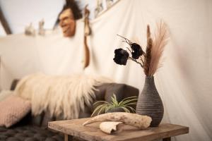 un jarrón con flores sobre una mesa en la sala de estar en Slapen tussen de schapen in de Tante Tipi, en Zennewijnen