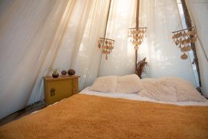 a bedroom with a bed with white sheets and pillows at Slapen tussen de schapen in de Tante Tipi in Zennewijnen