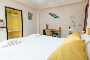 een witte slaapkamer met een groot wit bed met gele kussens bij Appartamento Georgiana in Taormina