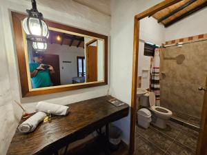 a woman taking a picture of a bathroom with a mirror at Cabañas y Hostal Bonanza mesa de los santos in Los Santos