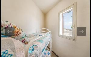 Habitación pequeña con cama y ventana en Una finestra sul mare, en Maragani