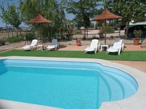 a swimming pool with lounge chairs and umbrellas at Finca - Granja " El Chaparral" in Orgaz
