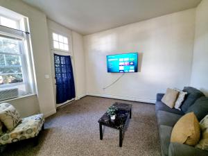 a living room with a couch and a tv on a wall at Lovely Spacious 1br Apt With Patio in Philadelphia