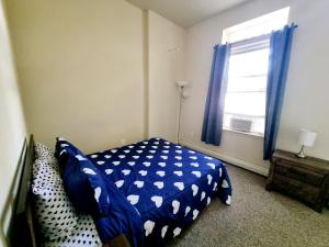 a bedroom with a bed with a blue comforter and a window at Lovely Spacious 1br Apt With Patio in Philadelphia