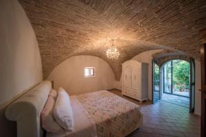 ein Schlafzimmer mit einem großen Bett in einem Backsteinzimmer in der Unterkunft Casale Torre Madre in Assisi