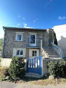 una casa di pietra con un cancello blu davanti di Maison en pleine nature a Saint-Maurice-en-Gourgois