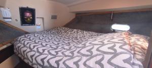 a bedroom with a bed with a black and white comforter at Nuit insolite sur l'eau au port de Ouistreham in Ouistreham
