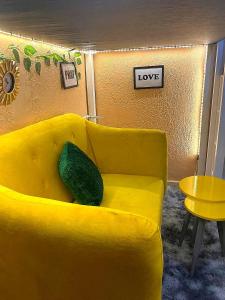 un sofá amarillo en una sala de estar con un signo de amor en Petite paradise, en Kampala