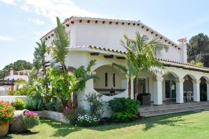 een wit huis met palmbomen in de tuin bij Villa Stella Maris Luxury 4BR Pool Beach in Roda de Bará
