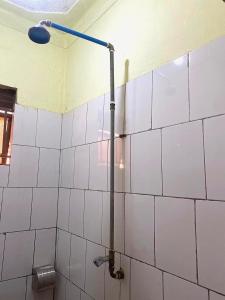 baño con una pared de azulejos blancos con pipa en Petite paradise, en Kampala