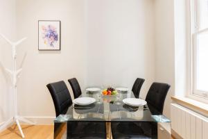 a dining room with a glass table and black chairs at Soho - Central London - CityApartmentStay in London