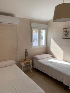 um quarto com 2 camas e uma janela em CASA CON TERRAZA, BARBACOA y WIFI PARA 7 PERSONAS em Ayamonte