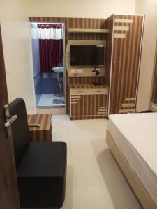 a bedroom with a bed and a tv and a chair at HOTEL R K RESIDENCY MUZAFFARPUR in Muzaffarpur