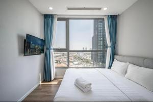a bedroom with a bed with a large window at Vinhome Landmark Suites in Ho Chi Minh City