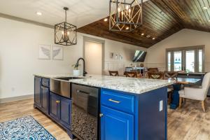uma cozinha em plano aberto com armários azuis e uma sala de jantar em The Periwinkle - 344 Audubon home em Dauphin Island
