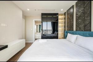 a bedroom with a large white bed with a blue headboard at Vinhome Landmark Suites in Ho Chi Minh City