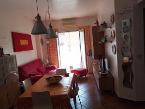 a living room with a table and a red couch at Smart Apartment by the Sea near Palermo, Sicily in Isola delle Femmine