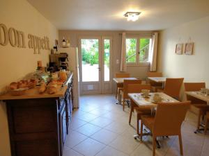 una sala da pranzo con tavoli e sedie e una cucina di La Colline - Chambre d'hôtes - B&B a Sarlat-la-Canéda