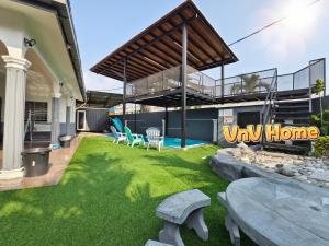 un cortile con prato verde e sedie e un edificio di Melaka-Private Pool/19pax Vacation Home/BBQ a Paya Rumput