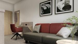 a living room with a couch and a red chair at C & N Hotel - an der Messe München in Munich