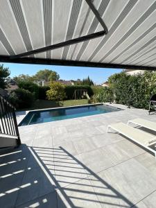 a patio with a swimming pool with awning at Belle maison avec piscine à 30 min de Paris in Yerres