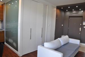 uma sala de estar com um sofá branco e uma porta de vidro em Apartament Mokotow em Varsóvia