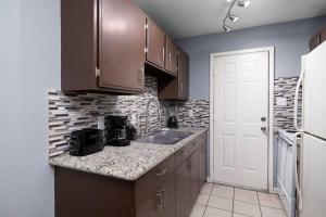 a kitchen with brown cabinets and a sink and a refrigerator at Oak Ridge 5 in McAllen
