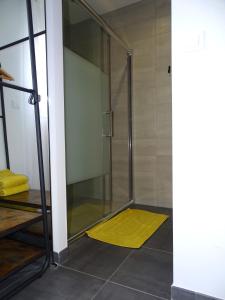 eine Dusche mit einer Glastür und einem gelben Teppich in der Unterkunft Gite Les Intemporels in Cuisery
