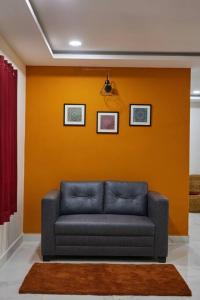 Sofá azul en una habitación con pared naranja en Pent House 1BHk @WiproCircle, Near US Embassy, Gachibowli en Hyderabad