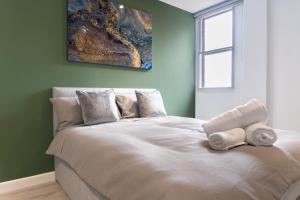Cross Street Suites by DH ApartHotels في بيتيربورو: غرفة نوم بسرير كبير عليها مناشف