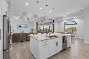 a kitchen with white cabinets and a living room at Gulf Access, Heated Saltwater Pool, Kayaks - Villa Sunset Lagoon in Matlacha