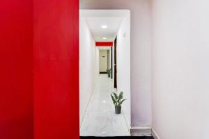 a hallway with red and white walls and a potted plant at OYO Flagship White Inn Near Golden Tower in Chennai
