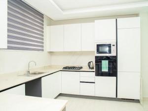 a kitchen with white cabinets and a black microwave at SERENE HAVEN RETREAT in Accra