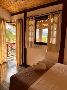 a bedroom with a bed and a window with a view at Pousada Chalés Sinbad in Ilhabela