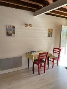 ein Esszimmer mit einem Tisch und 2 roten Stühlen in der Unterkunft La Treille in Lainsecq
