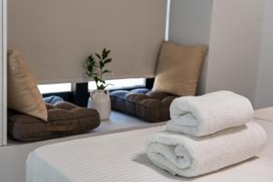 una pila di asciugamani appoggiata sopra un letto di Aelia Elegant Apartments a Kalamáta