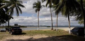 two cars parked on a beach with palm trees at Apartamento Favo de Mel 1 in Suape