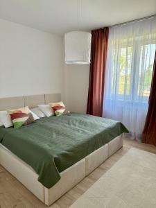 een slaapkamer met een groot bed en een groene deken bij Apartment ZANzi in Šamorín