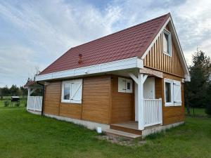 a small wooden house with a red roof at Dom Pod Żurawiami in Zgniłocha