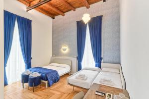 Toto e Peppino luxury rooms في نابولي: سريرين في غرفة مع ستائر زرقاء