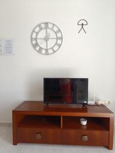 TV en un armario de madera con reloj en la pared en Vera Natura Apartamento Isabel, en Vera