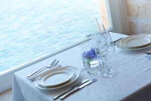 a white table with plates and glasses and a window at Hotel Don Ferrante in Monopoli