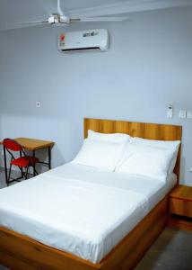 1 cama con cabecero de madera y silla roja en Estben guesthouse, en Kwabenyan