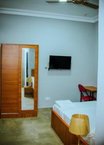 1 dormitorio con 1 cama y TV en la pared en Estben guesthouse, en Kwabenyan