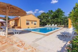 einen Pool mit Stühlen und einem Sonnenschirm in der Unterkunft Ferienhaus für 10 Personen in Paradiž bei Vodnjan, Istrien Südküste von Istrien in Juršići