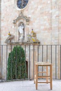 a chair sitting in front of a building with a clock at Hostal Boutique Sa Nansa in Tossa de Mar