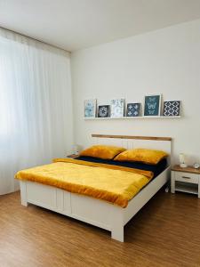 een witte slaapkamer met een bed met een gele deken bij Studio Apartment Bluebell in Bratislava