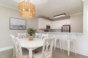 a kitchen and dining room with a white table and chairs at 311B - True Beachfront w/ Private Walkway and Pool in Myrtle Beach