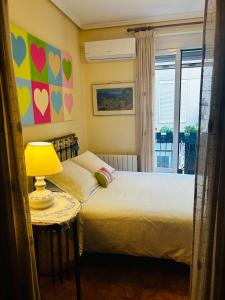 a bedroom with a bed with a lamp and a window at HABITACIÓN DOBLE o TRIPLE CORAZON DE RUZAFA in Valencia