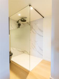 a bathroom with a glass shower with marble walls at Lace Hotel in Bruges